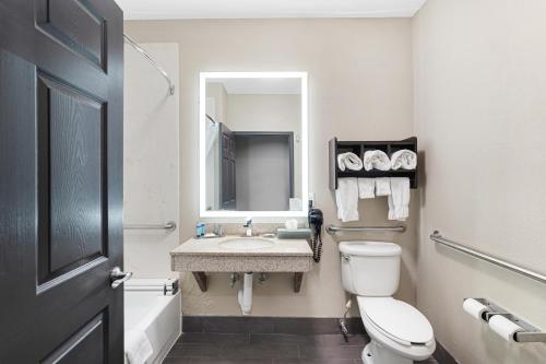 a bathroom with a toilet and a sink and a mirror at La Quinta by Wyndham Houston Hobby Airport in Houston