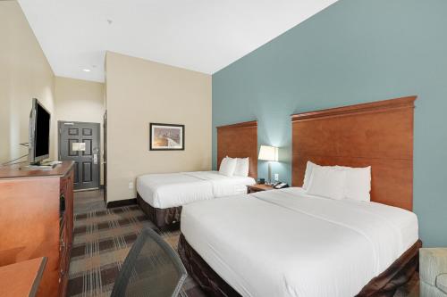 a hotel room with two beds and a television at La Quinta by Wyndham Houston Hobby Airport in Houston