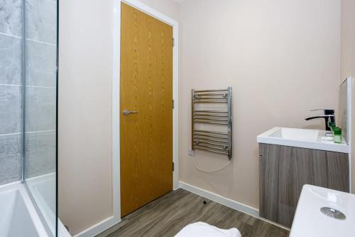 La salle de bains est pourvue d'un lavabo et d'une porte en bois. dans l'établissement Modern 1 Bedroom Apartment, Manchester, à Manchester