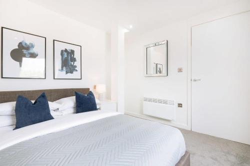 a white bedroom with a large bed with blue pillows at Modern 1BR Top Floor Apartment in Ipswich in Ipswich
