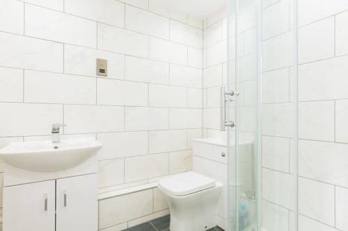 Baño blanco con aseo y lavamanos en Modern 1BR Top Floor Apartment in Ipswich, en Ipswich