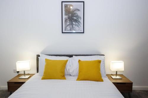 a bedroom with a bed with yellow pillows and two lamps at Contemporary 1 Bed Apartment Central Bolton in Bolton