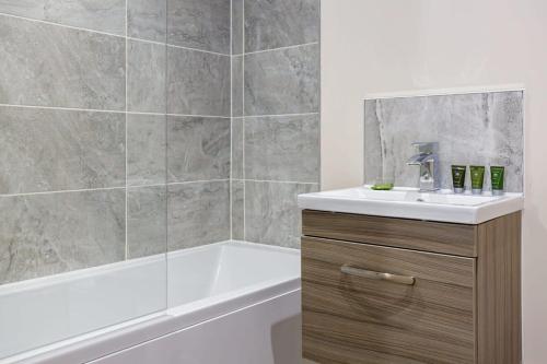 y baño con bañera, lavamanos y ducha. en Modern 2 Bedroom Apartment Manchester, en Mánchester