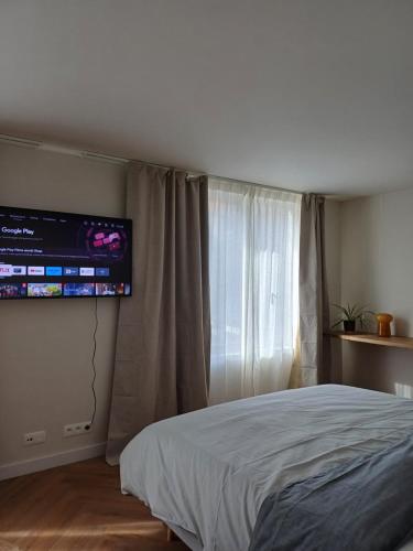 1 dormitorio con 1 cama y TV en la pared en The Bakery en De Haan