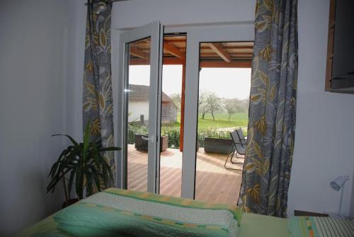 een slaapkamer met een glazen schuifdeur naar een patio bij Hiška Mirna ravnica in Moravske-Toplice