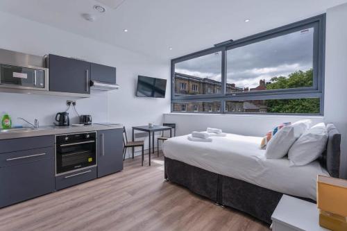 ein Schlafzimmer mit einem Bett und eine Küche mit einem großen Fenster in der Unterkunft Charming Studio Apartment in Central Sheffield in Sheffield