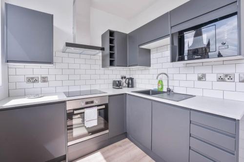 a white kitchen with a sink and a stove at Modern and Bright Studio in Central Sheffield in Sheffield