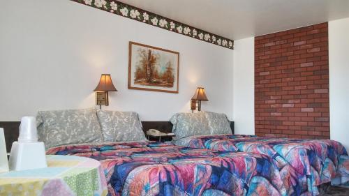 a bedroom with two beds and a brick wall at American Inn Motel Canon City in Canon City