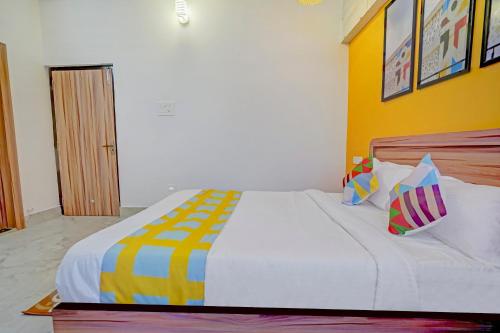 een slaapkamer met een groot wit bed met kleurrijke kussens bij OYO Home Luxury Stay Near Cosmopolis in Khandagiri