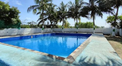a large blue swimming pool with palm trees at 4 Bedrooms Resort with Swimming Pool in Covelong