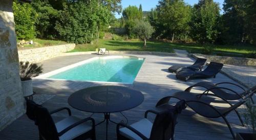 un patio con mesa y sillas junto a una piscina en Le Relais du Vivarais, en Viviers