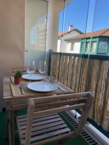 - une table en bois avec 2 verres à vin sur le balcon dans l'établissement Appartement baie de Chingoudy, à Hendaye