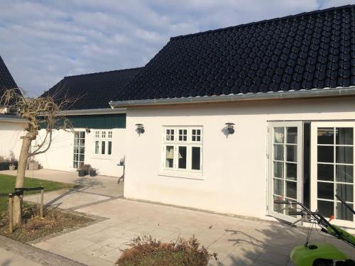 a white house with a black roof at Cozy, quiet guest house perfect for business or pleasure in Hillerød