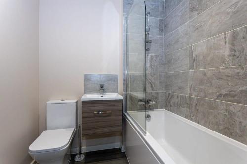 een badkamer met een bad, een toilet en een douche bij Contemporary 2 Bed Apartment Salford in Manchester