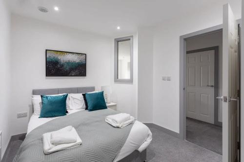 ein weißes Schlafzimmer mit einem großen Bett mit blauen Kissen in der Unterkunft Cosy 1 Bed Apartment in Leeds in Leeds