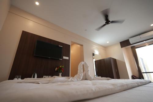 a bedroom with a bed with a flat screen tv on the wall at Hotel New Sagar Priya in Digha