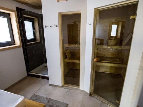Un baño con dos puertas de cristal y un lavabo. en "NisseHus" Comfortable holiday residence, en Gjerstad