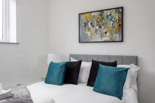 a white bed with blue pillows and a painting on the wall at Charming 1 Bed Apartment in Leeds in Leeds