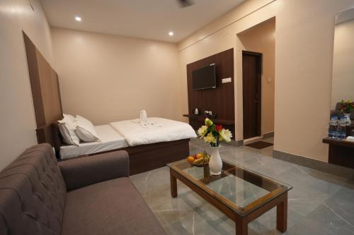 a hotel room with a bed and a couch and a table at Hotel New Sagar Priya in Digha