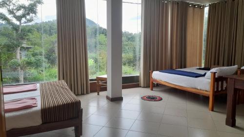 a bedroom with two beds and a large window at Dew Lee Homestay in Ella