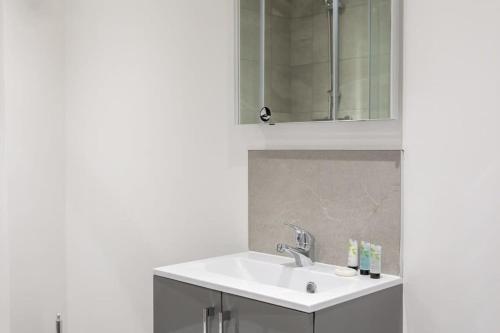 a white bathroom with a sink and a mirror at Cosy & Modern 1 Bed Apartment Leeds in Leeds