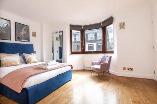 1 dormitorio con 1 cama azul y 1 silla en Spacious 1 Bed Mayfair Apartment with Balcony, en Londres
