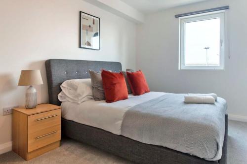 a bedroom with a bed with red pillows and a window at Lovely 1 Bedroom Apartment in Ashford in Ashford