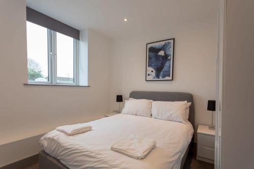 Amazing 1 Bedroom Apartment Leeds في ليدز: غرفة نوم بيضاء مع سرير عليه منشفتين