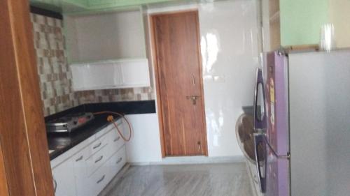 cocina con nevera y puerta de madera en Madiraju homestay en Kurnool