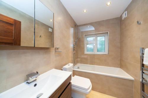 a bathroom with a sink and a toilet and a tub at Spacious 2 Bedroom Maisonette in Stratford in London