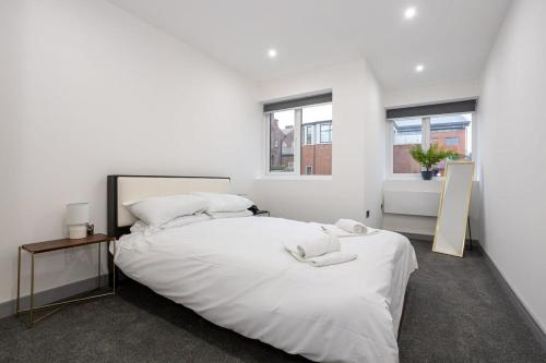 a white bedroom with a large bed and two windows at Fantastic 1 Bedroom Apartment in Preston Centre in Preston