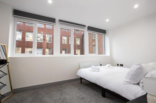 a bedroom with a white bed and two windows at Modern 1 Bedroom Apartment in Preston Centre in Preston