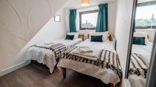 a bedroom with two beds and a mirror at Lovely 2 Bedroom Coastal Cottage near Bude in Bude