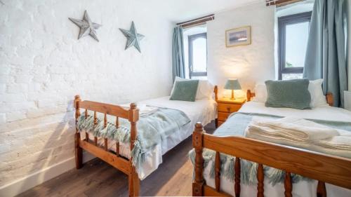 two twin beds in a bedroom with stars on the wall at Lovely 3 Bedroom Holiday Cottage nr Bude in Bude