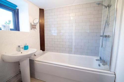 uma casa de banho com uma banheira, um lavatório e um chuveiro em Spacious 2 Bedroom Coastal Cottage nr Bude em Bude