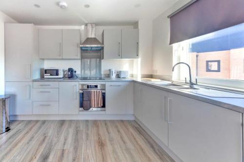 a white kitchen with white cabinets and a sink at Contemporary 2 Bedroom Apartment in Ashford in Ashford