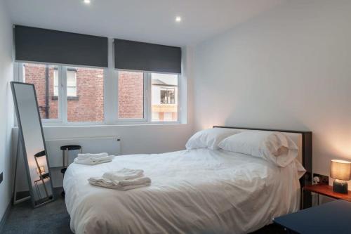 ein Schlafzimmer mit einem weißen Bett mit Handtüchern darauf in der Unterkunft Lovely 1 Bedroom Apartment in Preston in Preston