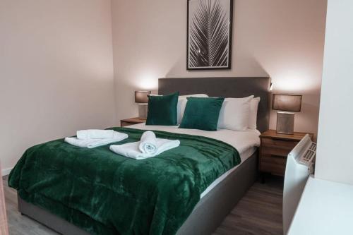 um quarto com uma cama com lençóis verdes e toalhas em Modern 2 Bed Apartment in Manchester - Sleeps 4 em Manchester