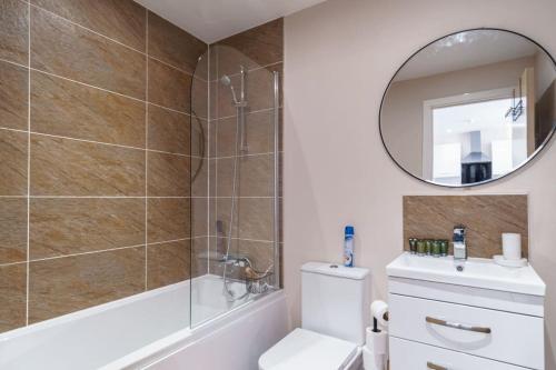 ein Bad mit einer Dusche, einem WC und einem Spiegel in der Unterkunft Lovely 1 Bedroom Manchester Apartment in Manchester