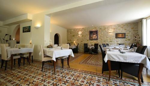 um restaurante com mesas e cadeiras brancas num quarto em Le Relais du Vivarais em Viviers