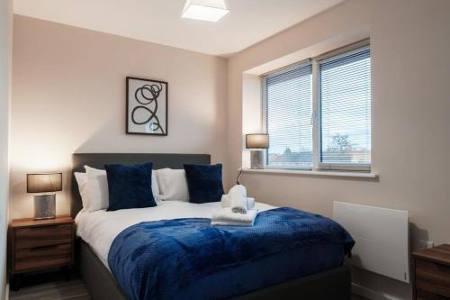 um quarto com uma cama com lençóis azuis e uma janela em A Lovely Modern 1 Bed Apartment in Manchester em Manchester