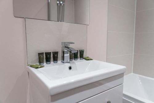 La salle de bains blanche est pourvue d'un lavabo et d'un miroir. dans l'établissement A Lovely Modern 1 Bed Apartment in Manchester, à Manchester