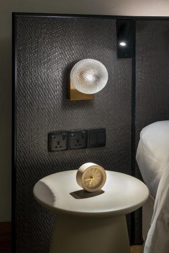 a clock on a table next to a bed at Else Kuala Lumpur, a member of Design Hotels in Kuala Lumpur