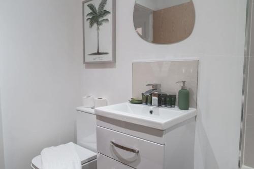 a white bathroom with a sink and a mirror at Lovely 2 Bed Apartment in Manchester - Sleeps 4 in Manchester