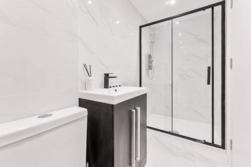 a white bathroom with a sink and a shower at Cosy 1 Bedroom Apartment in Burton-on-Trent in Burton upon Trent
