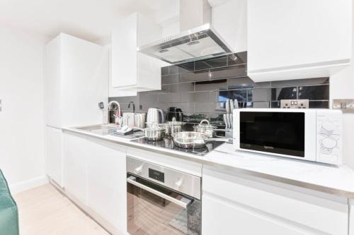 a kitchen with white cabinets and a microwave at Cosy 1 Bedroom Apartment in Burton-on-Trent in Burton upon Trent