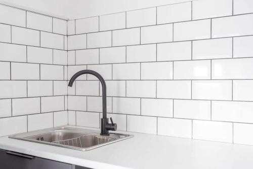 uma cozinha com um lavatório e uma parede de azulejos brancos em Modern 2 Bedroom Apartment in Central Bradford em Bradford