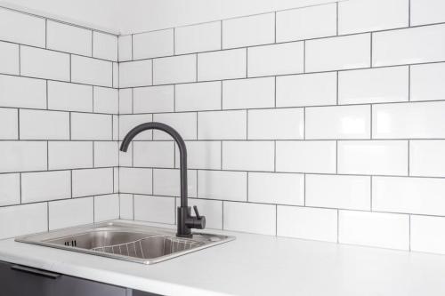 a kitchen with a sink and white tiled wall at 2 Bed Apartment Close to Bradford City Centre in Bradford