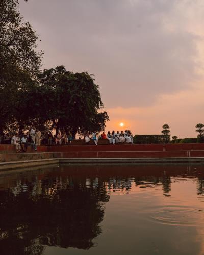 a group of people sitting around a pond at sunset at Hokke Lumbini in Lumbini
