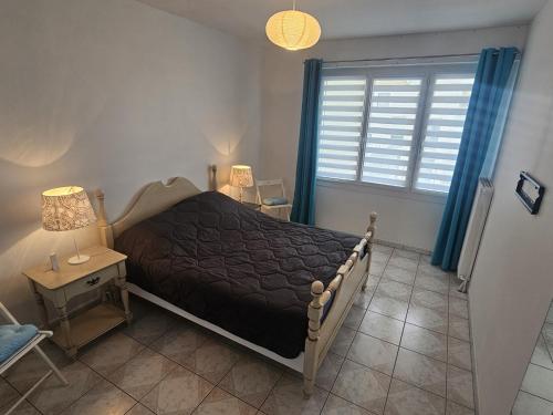 une chambre avec un lit et une fenêtre avec des rideaux bleus dans l'établissement Spacieux appartement 2 chambres à 450m de la plage et près du centre de Royan - FR-1-71-75, à Royan